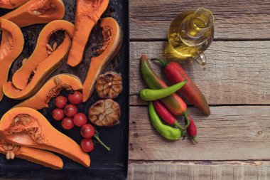 Balkabağı geleneksel sonbahar yemekleri. Kızarmış baharat, zeytinyağı, otlar ile ızgara kabak pişmiş. Bir fırın tepsisinde kavrulmuş sebze, rustik ahşap eski masada. Kopyalama alanı ile üstte görünüm.