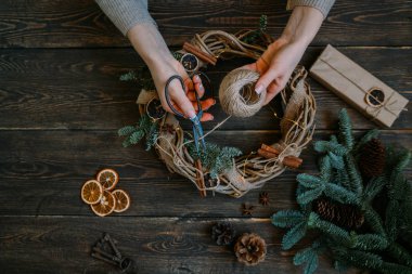 Süslemeleri, çelenk ve çam kozalağı ile Noel arka plan. Koyu vintage ahşap tahta üzerinde noel ağacı dalları ve kuru baharat yapılmış çelenk oluşturma. Yeni Yılınız Kutlu Olsun. Tonlu görüntü. Yumuşak odaklama.