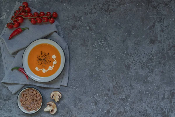 Geleneksel sonbahar yemekleri, kabak çekirdeği ve gri taş masada krem ile sıcak ve baharatlı kabak çorbası. Sonbahar yemeği. Organik sebzeler ve sağlıklı gıda konsepti. Kopyalama alanı ile üst görünüm. Tonlu görüntü
