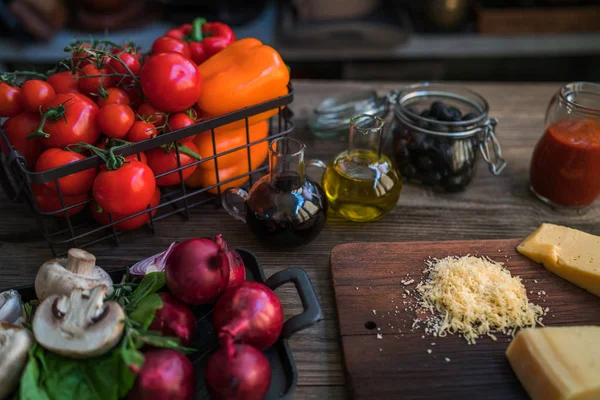 Food ingredients and spices for cooking. Mushrooms, tomatoes, cheese, onion, oil, pepper, salt, basil, olive. on rustic wooden background. Healthy foods, cooking concept. Toned image.