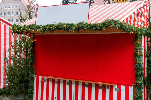 Decorated Christmas fair kiosk with fir branches and garland, no logos. Christmas decorations on the Christmas market in front of City Town Hall in Munich, Bavaria. Free space for you text.