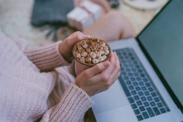 Winter hot drinks. Female hands holding cup of coffee or hot chocolate. Warm pink sweater, home comfort and relax. Christmas holidays, hot drinks and people concept. Toned image. Selective focus.