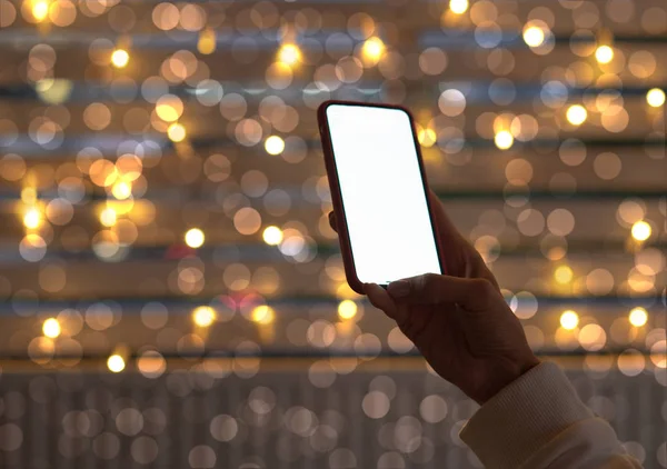 Woman using her mobile phone in the street, Christmas night light background.