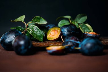 Bahçe erikleri masada. Yaprakları ile taze erik kapatın. Erik yaz veya sonbahar hasadı. Tonlu görüntü. Seçici odaklama.