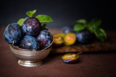 Masada olgun sulu erik ile Bowl. Taze organik erik. Yaz hasadı. Sonbahar hasadı. Güzel natürmort. Tonlu görüntü. Seçici odaklama.