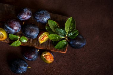 Bahçe erikleri masada. Yaprakları ile taze erik kapatın. Erik yaz veya sonbahar hasadı. Tonlu görüntü. Seçici odaklama.