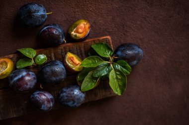 Koyu arka planda yeşil yaprakları ile kırmızı kiraz erik. Kopyalama alanı ile tonlu görüntü.