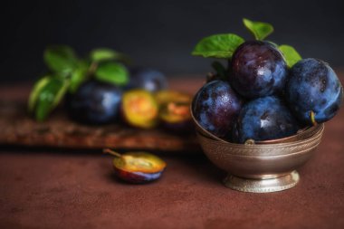 Masada olgun sulu erik ile Bowl. Taze organik erik. Yaz hasadı. Sonbahar hasadı. Güzel natürmort. Tonlu görüntü. Seçici odaklama.