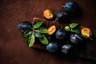 Koyu arka planda yeşil yaprakları ile kırmızı kiraz erik. Kopyalama alanı ile tonlu görüntü.