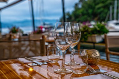 Gözlük ve peçete ile masa ayarı. Portofino, İtalya'da açık hava restoranırahat iç. Rahat bir yemek mekanı. Gün batımında iki kisi lik romantik masa. Sahilde restoran.