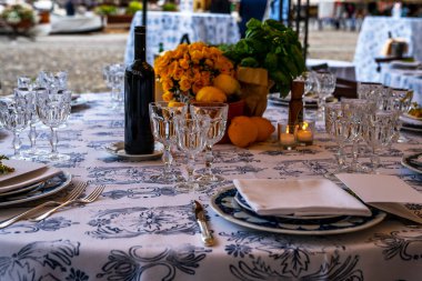 Düğün. Ziyafet. Konuklar, yuvarlak masa ve sandalyeler çatal bıçak takımı, çiçekler ve çanak çömlek ile servis ve bir masa örtüsü ile kaplı.