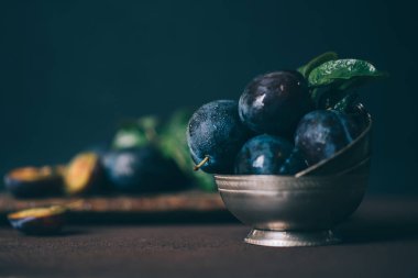 Kahverengi yüzey arka plan üzerinde gümüş vintage kase Organik taze erik. Sağlıklı yaşam tarzı yaz vejetaryen gıda. Kır bahçe meyve konsepti. Güzel natürmort. Kopyalama alanı ile tonlu görüntü.