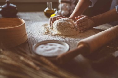 Doğal ışık ile ahşap bir yüzeyüzerinde ekmek veya pizza için hamur. Koyu ahşap arka plan üzerinde Eller pişirme hamuru. Gıda konsepti. Seçici odaklama.
