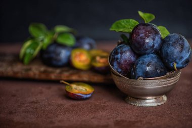 Kahverengi yüzey arka plan üzerinde gümüş vintage kase Organik taze erik. Sağlıklı yaşam tarzı yaz vejetaryen gıda. Kır bahçe meyve konsepti. Güzel natürmort. Kopyalama alanı ile tonlu görüntü.