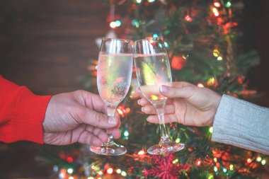 Şerefe! Womam ve adam arka planda Noel iç şampanya flüt ile tezahürat. Tatil konsepti. Akşam ışıkları parlıyor. Yeni yıl kutlaması. Tonlu görüntü. Seçici odaklama.