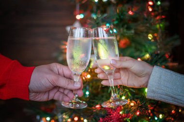 Noel aydınlatmaları ve şampanya bardağı. Bardak şampanya, kutlama ve Noel ve mutlu yeni yıl onuruna kızartma insanlarla elleri. Şampanya flüt ile tezahürat çift.