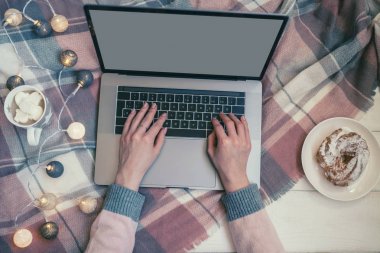 Bilgisayarlı çalışma alanı, kız elleri, fincan sıcak çikolata, beyaz renkli kek tepsisi, beyaz arka planda noel dekoru. Serbest çalışan bir iş yeri. Mutlu Noeller! Üst Manzara. Seçici odak.