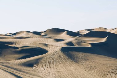 Çölde güzel kum tepeleri dalgalanıyor, gün batımında sıcak kuru kum. Doğa manzarası. Huacachina çölü, Ica Bölgesi, Peru. Tonlu görüntü.