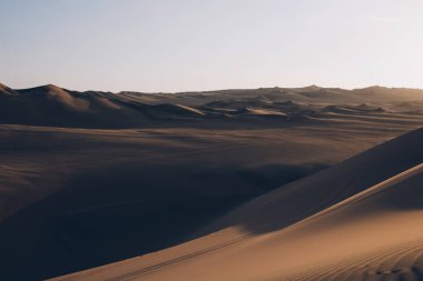 Çölde güzel kum tepeleri dalgalanıyor, gün batımında sıcak kuru kum. Doğa manzarası. Huacachina çölü, Ica Bölgesi, Peru. Tonlu görüntü.