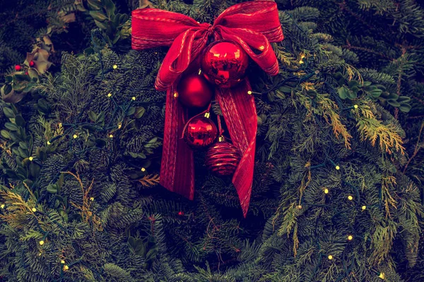 スプルースの枝から緑のクリスマスリースと赤いリボンの弓と装飾とボール 赤で新鮮なモミの枝や装飾品で構成されています クリスマスと新年の休日の背景 — ストック写真