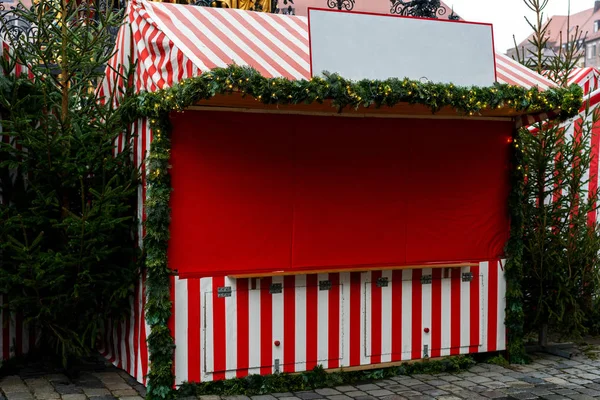 Decorated Christmas fair kiosk with fir branches and garland, no logos. Christmas decorations on the Christmas market in front of City Town Hall in Munich, Bavaria. Free space for you text.