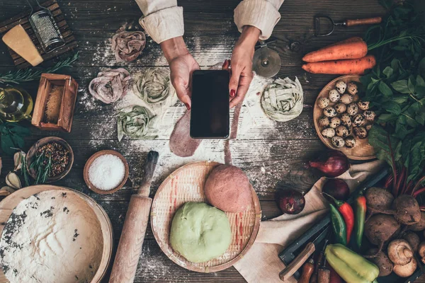 Food blogger concept. Young woman recording video on smartphone at kitchen. Woman recording every step of cooking process for her blog. Diet, technology, health, food, cooking, culinary, and people.