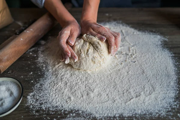 Woman baking homemade bread. Sprinkling some flour on dough. Hands kneading dough.