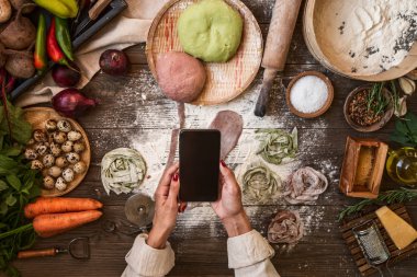 Yemek akıllı telefon resimleri ile Eller. Genç kadın, pişirme blogger ev mutfağında yemek ve akıllı telefon fotoğraf yapıyor. Instagram gıda blogger atölye konsepti.