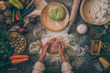 Kıdemli kadın restoran mutfakta hamur ile tagliatelle makarna yapma aşçı. Makarna yapıyorum. Restoranda makarna yapmak. Pancar, havuç ve ıspanak ile renkli çiğ sebze makarna.