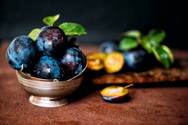 Bahçe erikleri masada. Yaprakları ile taze erik kapatın. Erik yaz veya sonbahar hasadı. Tonlu görüntü. Seçici odaklama.