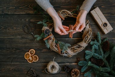 Noel kompozisyonu. Koyu ahşap rustik masaüzerinde el yapımı noel çelengi yapan kadın. Mutlu tatiller için hazırlık kavramı. Şenlikli iç dekor. Üst görünüm, kopya spaz ile düz yatıyordu