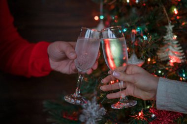 Noel ağacının yanında tatil ve birliktelik. Mutlu Noeller ve Mutlu Yıllar 2018! Noel partisi zamanı. Şampanyayla kadeh kaldıran bir çift. Kutlama konsepti, tatil arka planı, seçici odak.