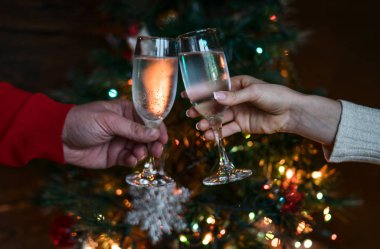 Noel ağacının yanında tatil ve birliktelik. Mutlu Noeller ve Mutlu Yıllar 2018! Noel partisi zamanı. Şampanyayla kadeh kaldıran bir çift. Kutlama konsepti, tatil arka planı, seçici odak.