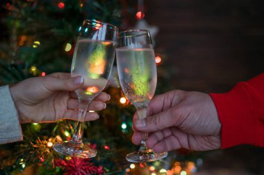 Noel ağacının yanında tatil ve birliktelik. Mutlu Noeller ve Mutlu Yıllar 2018! Noel partisi zamanı. Şampanyayla kadeh kaldıran bir çift. Kutlama konsepti, tatil arka planı, seçici odak.