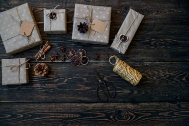 Rustik ahşap tahta üzerinde süslemeleri ve zanaat kağıt hediye kutuları ile Noel arka plan. Hediyeler, dekorasyon, köknar konileri, anason yıldız ve ip kurdele. Mutlu tatiller için hazırlık. Tonlu görüntü.