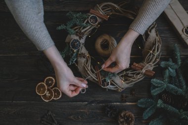 Noel kompozisyonu. Koyu ahşap rustik masaüzerinde el yapımı noel çelengi yapan kadın. Mutlu tatiller için hazırlık kavramı. Şenlikli iç dekor. Üst görünüm, kopya spaz ile düz yatıyordu