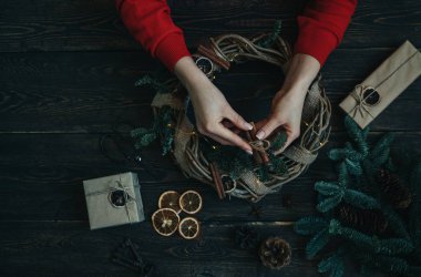 Noel kompozisyonu. Koyu ahşap rustik masaüzerinde el yapımı noel çelengi yapan kadın. Mutlu tatiller için hazırlık kavramı. Şenlikli iç dekor. Üst görünüm, kopya spaz ile düz yatıyordu