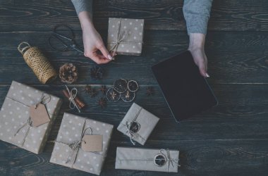 El yapımı Noel hediyeleri yaparken tablet kullanan bir kadın. Çevrimiçi öğrenme. Mutlu tatiller için hazırlık konsepti. Şölen dekoru. Kopyalama spazmı ile üst görünüm. Tonlanmış görüntü. Klasik stil.