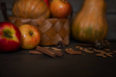 Baharat, sonbahar yaprakları ve sıcak koyu ahşap masa üzerinde koniler. Arka planda ufuk renkli sebze. Organik sebze hasır sepetin içinde. Çevre gıda ve hasat kavramı. Seçici odak.