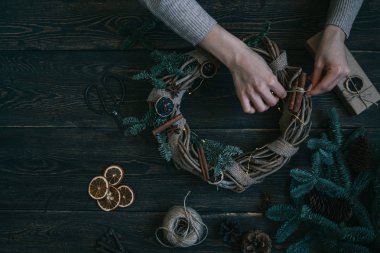 Süslemeleri, çelenk ve çam kozalağı ile Noel arka plan. Koyu vintage ahşap tahta üzerinde noel ağacı dalları ve kuru baharat yapılmış çelenk oluşturma. Yeni Yılınız Kutlu Olsun. Tonlu görüntü. Yumuşak odaklama.