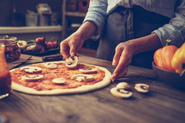Ellerini pişir. Ellere yakın, masanın etrafında bazı malzemeler. Taze orijinal İtalyan çiğ pizza, geleneksel tarzda hazırlık. Malzemeler ve baharatlar ahşap masada ev yapımı pizza yapmak için.