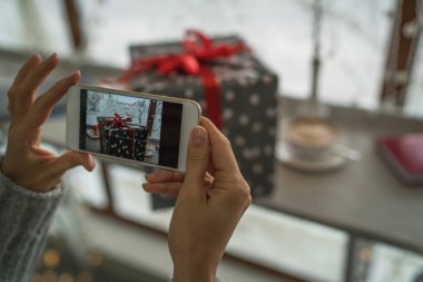 Genç bayan, blogcu tatil için hazırlanıyor ve akıllı telefonda fotoğraf çekiyor. Sosyal ağlarda cep telefonu tutan ve sohbet eden bir kadının elleri. Görüntü tonlaması. Seçici odak.