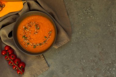 Geleneksel sonbahar yemekleri, kabak çekirdeği ve gri taş masada krem ile sıcak ve baharatlı kabak çorbası. Sonbahar yemeği. Organik sebzeler ve sağlıklı gıda konsepti. Kopyalama alanı ile üst görünüm. Tonlu görüntü
