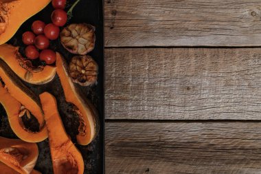 Balkabağı geleneksel sonbahar yemekleri. Kızarmış baharat, zeytinyağı, otlar ile ızgara kabak pişmiş. Bir fırın tepsisinde kavrulmuş sebze, rustik ahşap eski masada. Kopyalama alanı ile üstte görünüm.