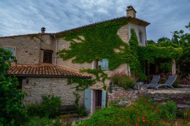 Güzel botanik bahçe bitkiler, renkli çiçekler ve aile ile açık oturma ve barbekü ile arka bahçesinde ile dekore edilmiştir. Alpes-de-Haute-Provence, Fransa'da eski bir evin pitoresk cephesi.