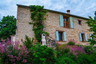 Güzel botanik bahçe bitkiler, renkli çiçekler ve aile ile açık oturma ve barbekü ile arka bahçesinde ile dekore edilmiştir. Alpes-de-Haute-Provence, Fransa'da eski bir evin pitoresk cephesi.