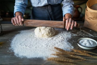 Kadın elleri top şeklinde hamur yapıyor. Doğal ışık ile ahşap masada tarafında malzemeler ile temel ev yapımı hamur. Ev sağlıklı gıda. Seçici odak. Hamura odaklanın.