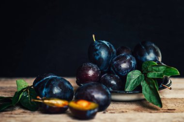 Bahçe erikleri masada. Yaprakları ile taze erik kapatın. Erik yaz veya sonbahar hasadı. Tonlu görüntü. Seçici odaklama.