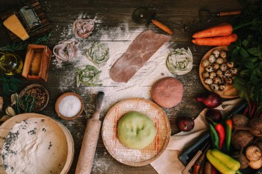 Koyu ahşap masa nın üst görünümünde makarna malzemeleri ile taze ev yapımı makarna. Koyu ahşap bir masa üzerinde İtalyan makarna tagliatelle. Pancar, havuç ve ıspanak ile renkli çiğ sebze makarna.