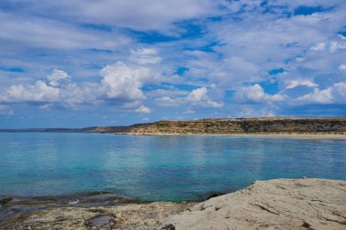 İspanya 'daki güzel ve renkli Mallorca adasındaki beyaz bulutlar ve dağ arka planıyla mavi turkuaz deniz suyu ve gökyüzü ile ıssız kayalıkların manzaralı manzarası..